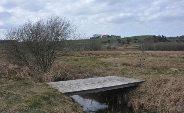 En bro fører stien over Kastbjerg å lige nord for voldstedet.