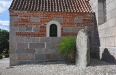 Den store runesten står opsat ved siden af kirkens våbenhus.