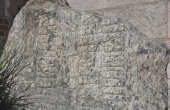 En del af runestenes top mangler, da den blev tilhugget til brugen som tærskelsten i kirken.